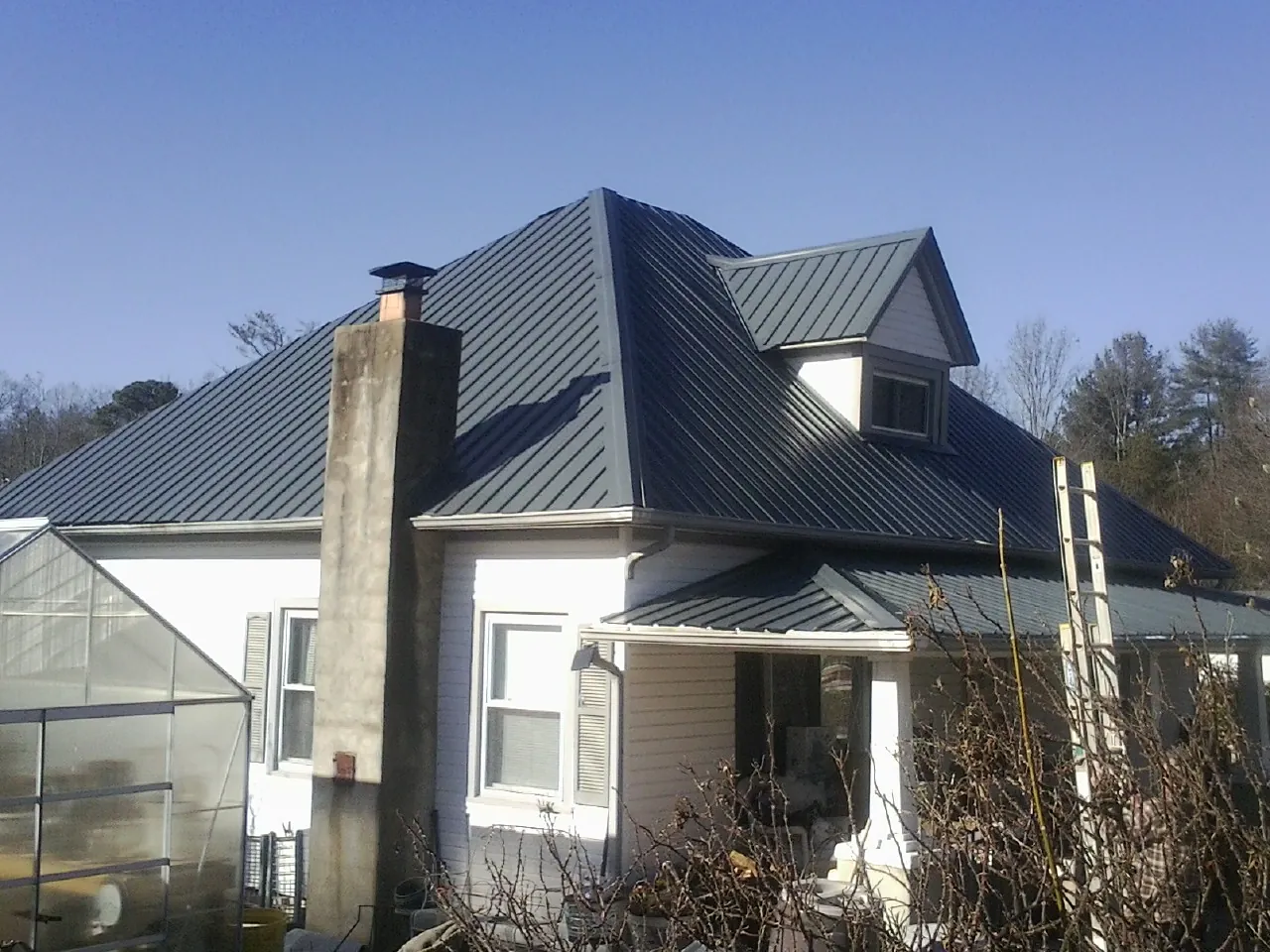 Dark blue standing seam metal roof on a white farmhouse with dormer — Slate & Tile Roof Repair by Roofing Brothers in San Jose