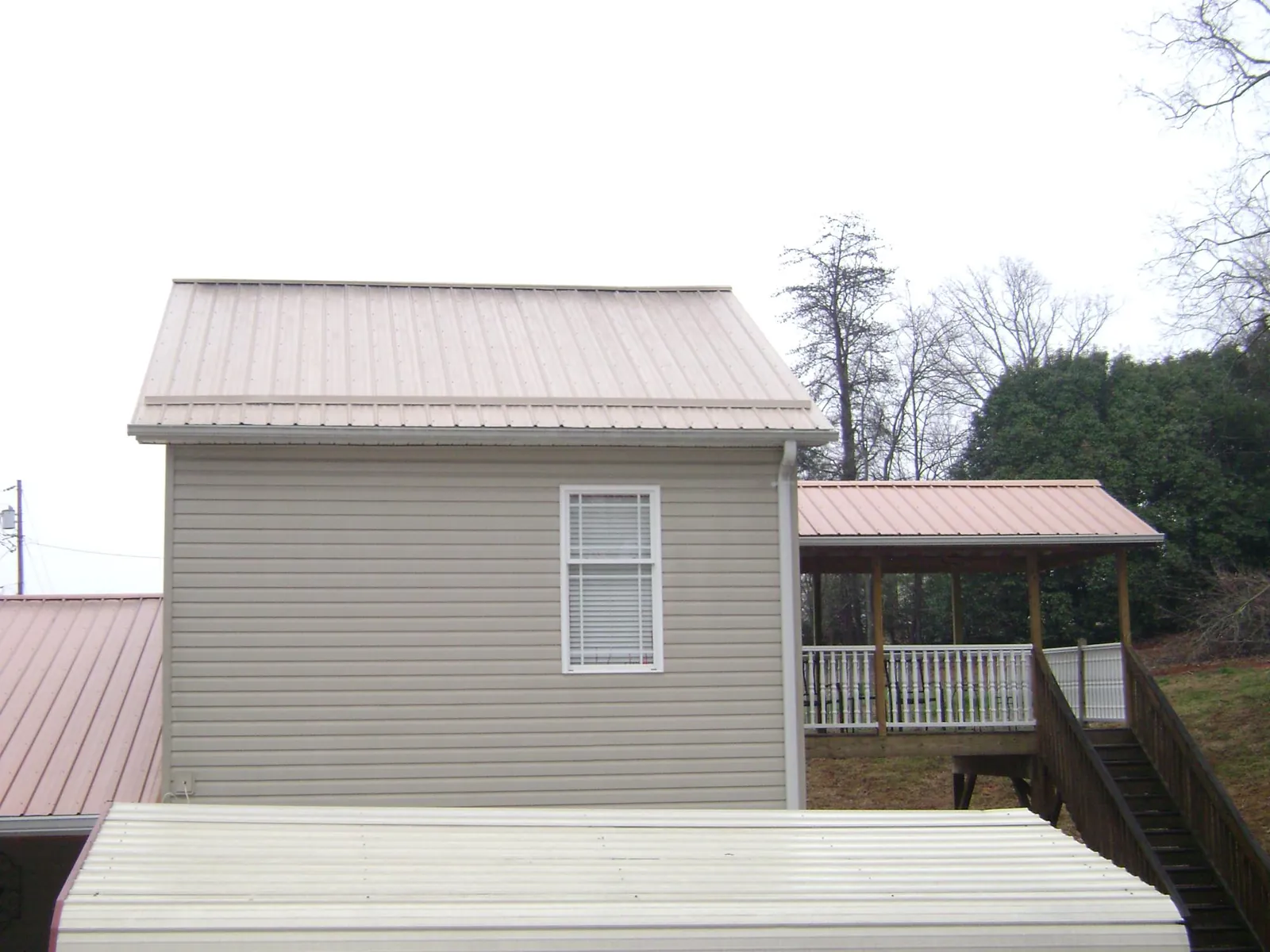 Tan metal roofs on a two story addition and attached porch, from a Roof Replacement job in San Jose